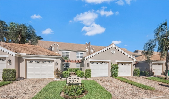 traditional-style home featuring a garage, decorative driveway, and stucco siding