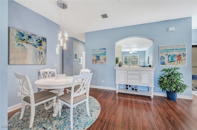 dining area featuring arched walkways, dark wood finished floors, visible vents, and baseboards