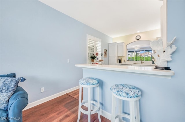 kitchen featuring a peninsula, a breakfast bar area, light countertops, and white cabinets