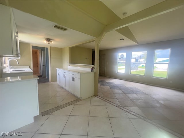 kitchen with sink, light tile patterned floors, and white cabinetry