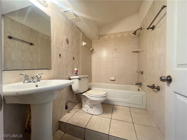 bathroom with tiled shower / bath, vaulted ceiling, tile patterned floors, toilet, and tile walls