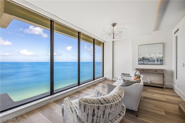 living area featuring a water view, an inviting chandelier, and hardwood / wood-style flooring