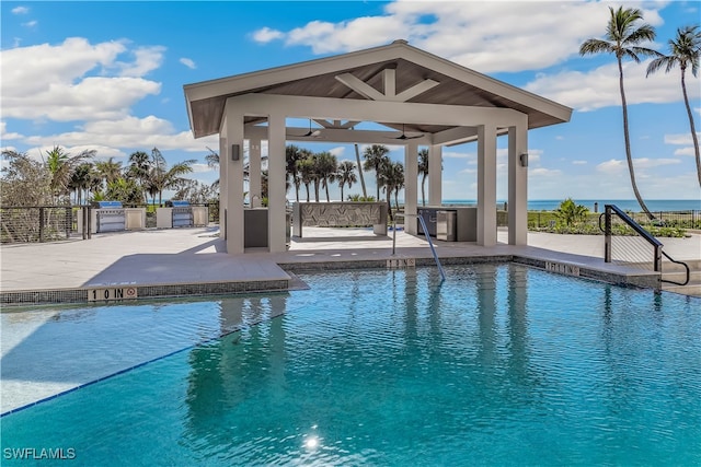 view of swimming pool featuring a gazebo, a water view, exterior kitchen, and a patio