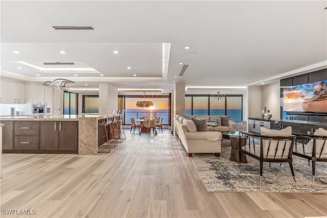 living room featuring light wood-type flooring and a tray ceiling