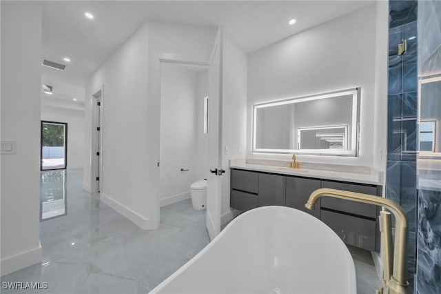 bathroom featuring a tub to relax in, toilet, and vanity