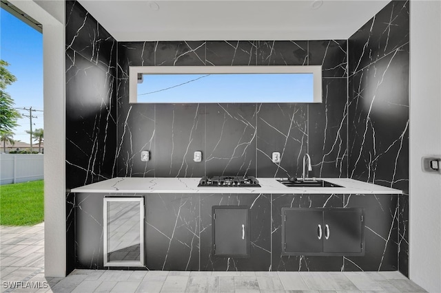 interior space featuring light stone counters, black gas stovetop, and sink