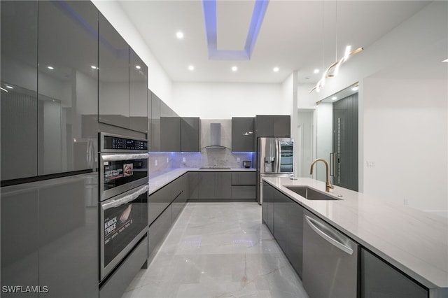 kitchen with gray cabinets, light stone counters, sink, wall chimney exhaust hood, and appliances with stainless steel finishes