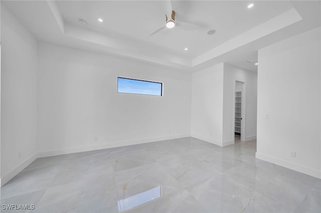 unfurnished room featuring ceiling fan and a tray ceiling