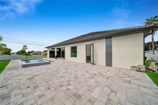 rear view of property featuring a patio area and a pool with hot tub