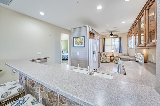 kitchen with ceiling fan, sink, white appliances, and kitchen peninsula