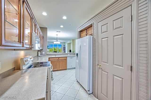 kitchen featuring white appliances, sink, hanging light fixtures, light tile patterned flooring, and kitchen peninsula