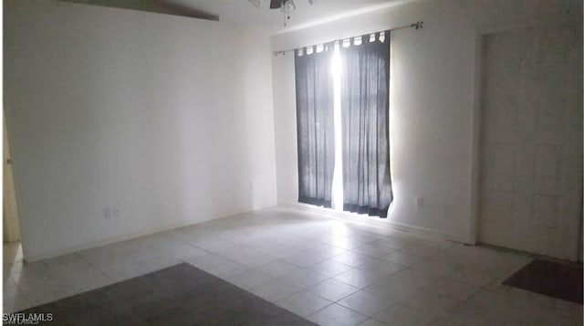 tiled empty room featuring ceiling fan