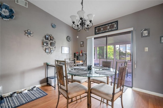 dining room featuring hardwood / wood-style flooring, lofted ceiling, and an inviting chandelier