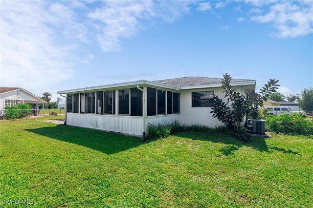 rear view of property featuring a lawn, central air condition unit, and a sunroom