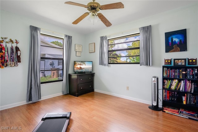 exercise room with ceiling fan and light wood-type flooring