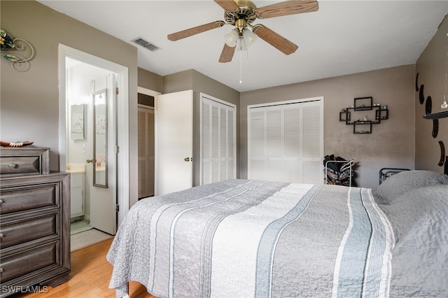 bedroom with ceiling fan, light hardwood / wood-style floors, and two closets