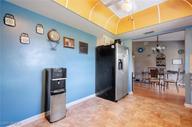 kitchen featuring stainless steel refrigerator with ice dispenser, ceiling fan with notable chandelier, and hanging light fixtures