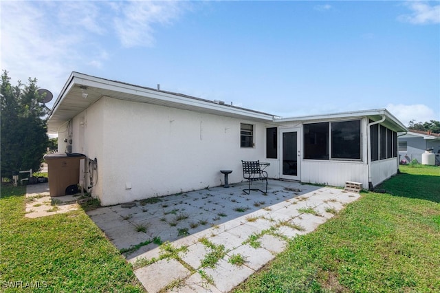 rear view of property featuring a lawn, a sunroom, and a patio area