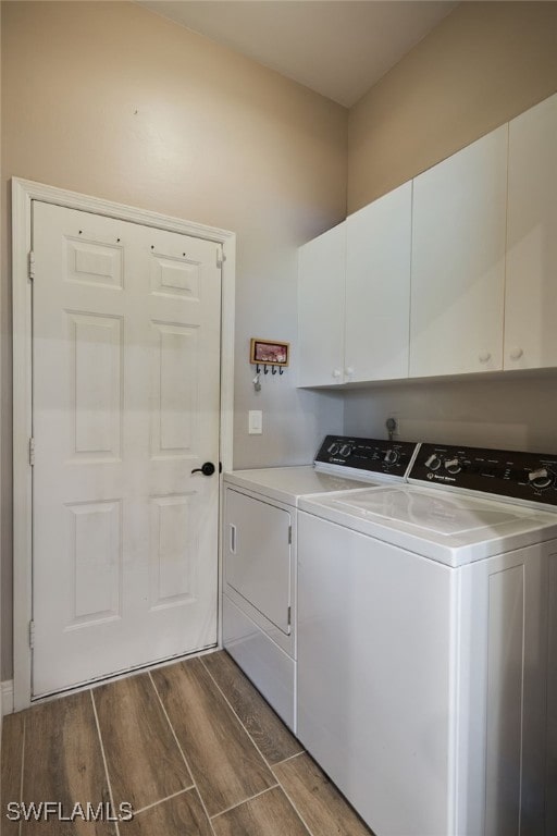 clothes washing area with dark hardwood / wood-style floors, washer and dryer, and cabinets