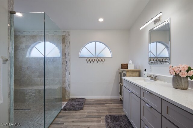 bathroom featuring a tile shower, vanity, hardwood / wood-style floors, and a wealth of natural light