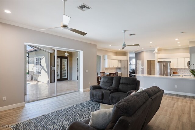 living room with ornamental molding, light hardwood / wood-style floors, ceiling fan, and plenty of natural light