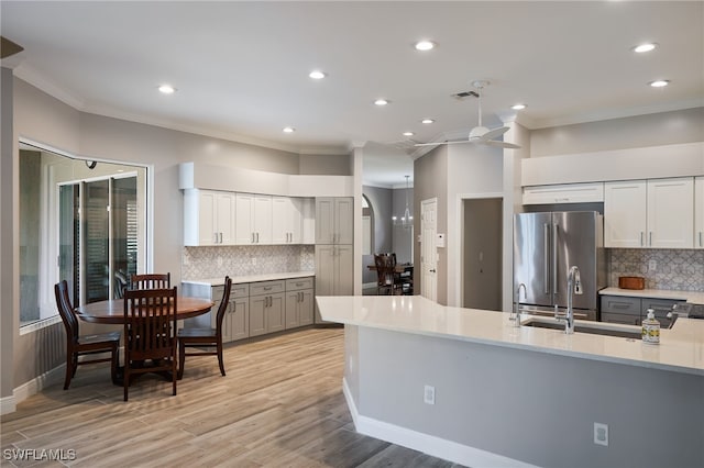 kitchen featuring ornamental molding, light wood-type flooring, backsplash, and high quality fridge