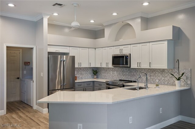 kitchen featuring washer and clothes dryer, kitchen peninsula, ceiling fan, and stainless steel appliances