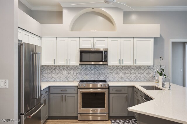 kitchen featuring sink, tasteful backsplash, gray cabinets, stainless steel appliances, and crown molding