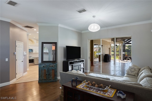 living room with a notable chandelier, light wood-type flooring, and crown molding