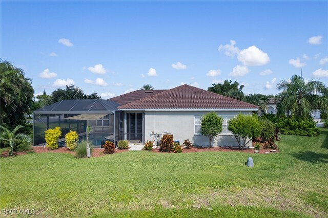 back of house with a lanai and a yard