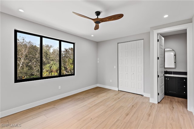 unfurnished bedroom featuring a closet, ensuite bathroom, light hardwood / wood-style flooring, and ceiling fan