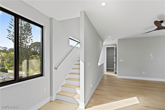 stairway with ceiling fan, plenty of natural light, and hardwood / wood-style flooring