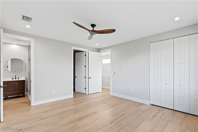 unfurnished bedroom with light wood-type flooring, connected bathroom, ceiling fan, and sink