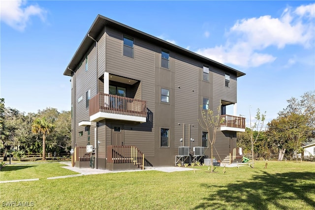 rear view of house with a balcony and a lawn