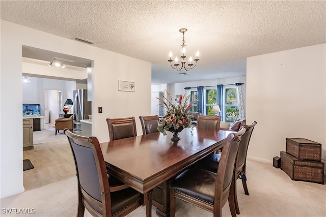 dining space featuring a textured ceiling, light carpet, and a chandelier