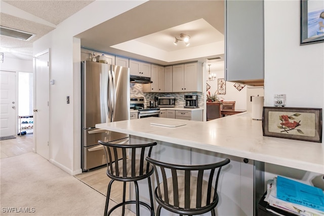 kitchen with a kitchen breakfast bar, tasteful backsplash, stainless steel appliances, and kitchen peninsula