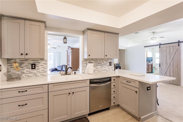 kitchen featuring stainless steel dishwasher, ceiling fan, a barn door, sink, and kitchen peninsula