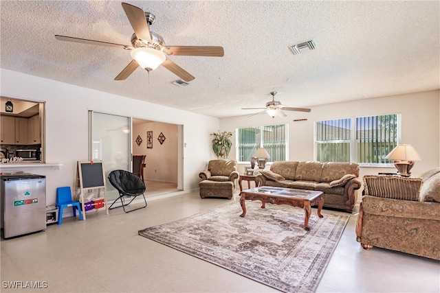 living room featuring plenty of natural light, ceiling fan, and a textured ceiling