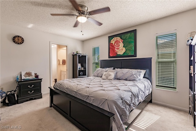 bedroom featuring light carpet, ceiling fan, a textured ceiling, and connected bathroom