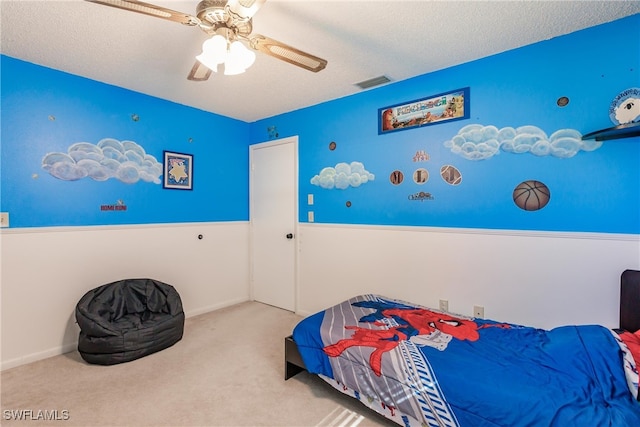 bedroom featuring light carpet, ceiling fan, and a textured ceiling