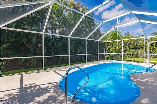 view of pool with a patio and glass enclosure