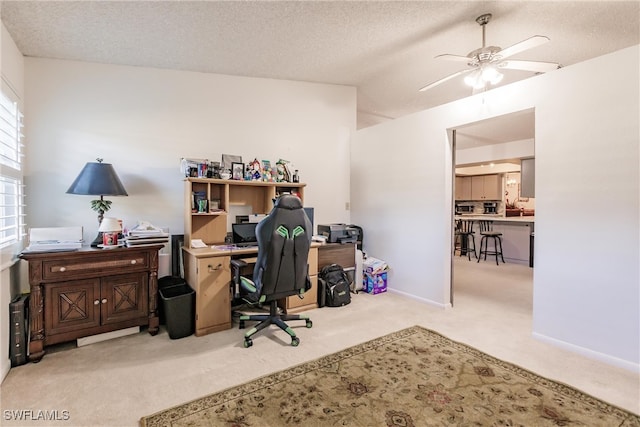 office area with a textured ceiling, light carpet, vaulted ceiling, and ceiling fan