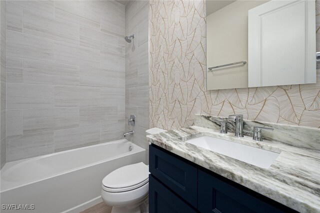 full bathroom featuring vanity, toilet, tiled shower / bath combo, and decorative backsplash