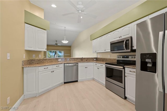 kitchen with light stone counters, stainless steel appliances, white cabinetry, ceiling fan, and light wood-type flooring