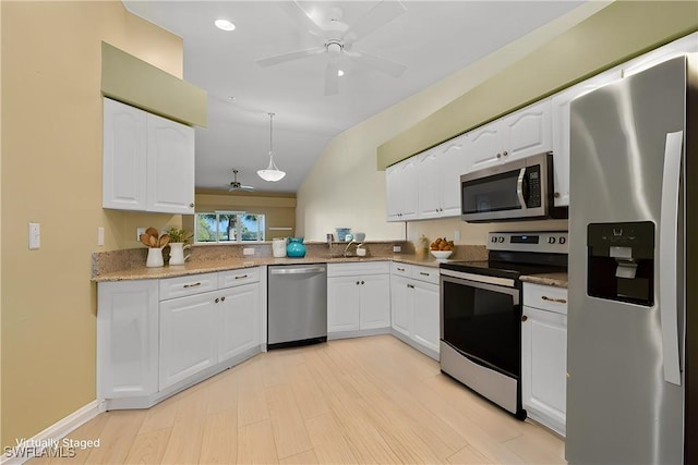 kitchen with lofted ceiling, stainless steel appliances, white cabinets, and pendant lighting