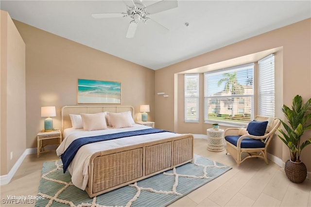 bedroom featuring light wood-style flooring, baseboards, vaulted ceiling, and a ceiling fan