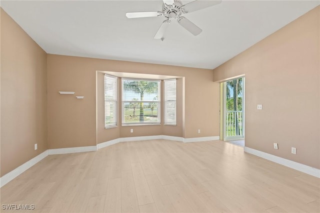 empty room featuring vaulted ceiling, light wood finished floors, a ceiling fan, and baseboards