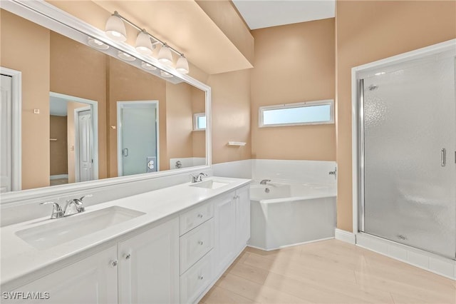 bathroom with a garden tub, a sink, a shower stall, and double vanity