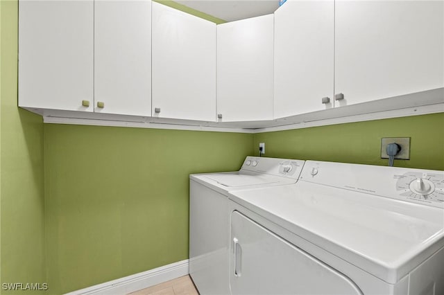 washroom featuring cabinets, light tile patterned floors, and washer and clothes dryer