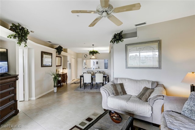 living area with light tile patterned flooring, visible vents, ceiling fan, and baseboards